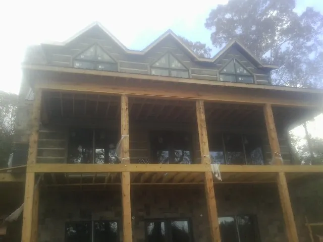 Dormers and porch framing on a large log home under construction — Roof Coating work by our crew in Harwood